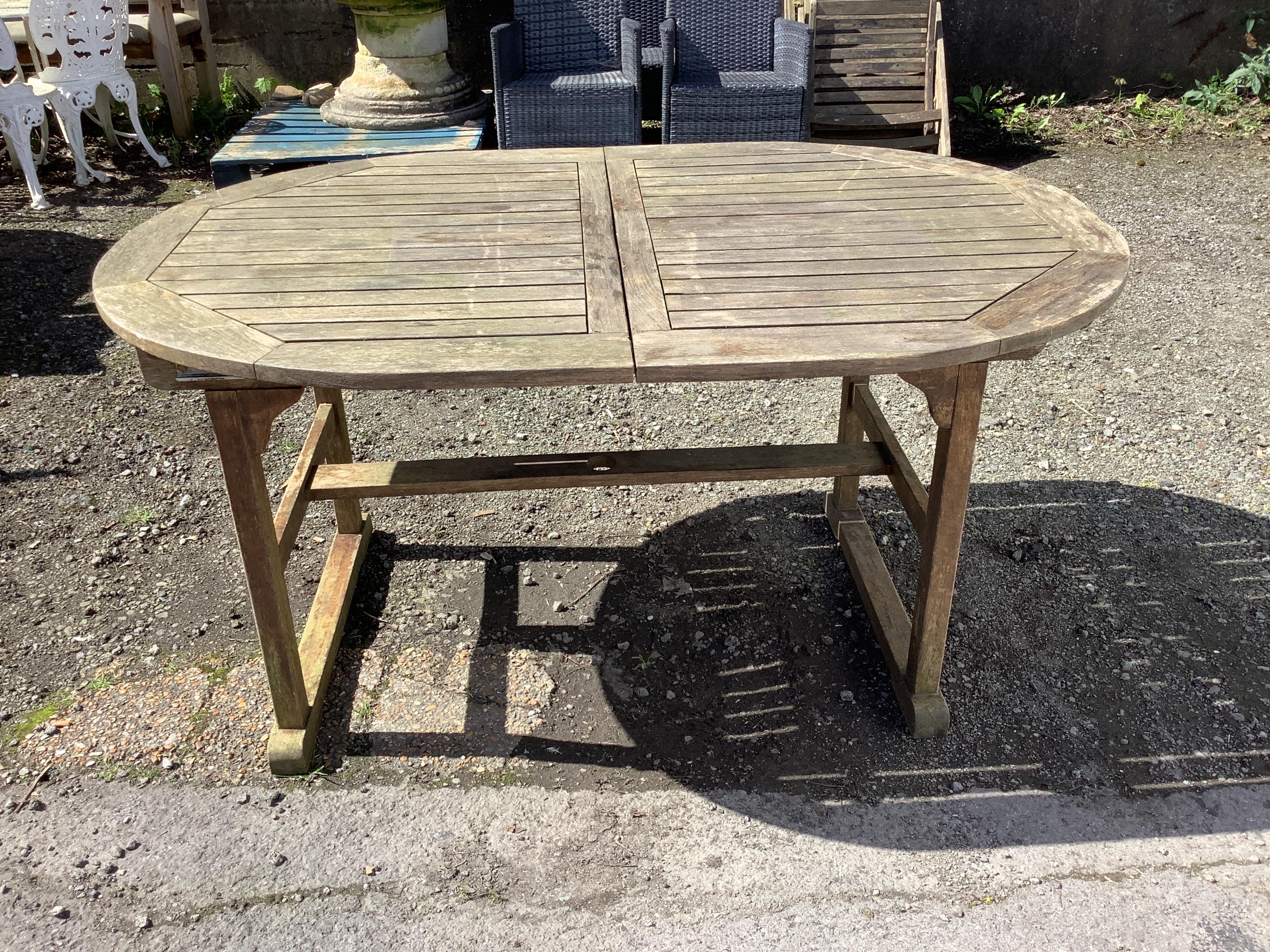 A weathered teak extending garden table, width 150cm, depth 100cm, height 74cm, together with six teak folding armchairs with seat pads